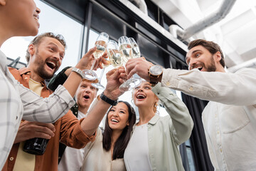 low angle view of cheerful business people clinking champagne glasses during corporate party