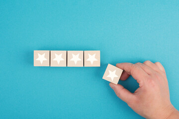 Stars rating, hand puts the last cube in the row, giving feedback, positive valuation
