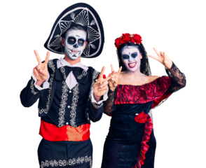 Young couple wearing mexican day of the dead costume over background smiling with tongue out showing fingers of both hands doing victory sign. number two.