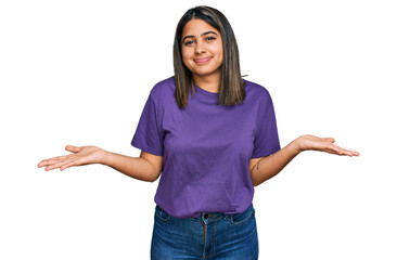 Young hispanic girl wearing casual purple t shirt clueless and confused expression with arms and hands raised. doubt concept.