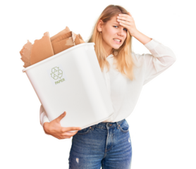 Young beautiful blonde woman holding recycle paper bin stressed and frustrated with hand on head, surprised and angry face