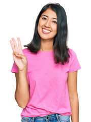 Beautiful asian young woman wearing casual pink t shirt showing and pointing up with fingers number three while smiling confident and happy.