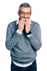 Middle age hispanic with grey hair wearing glasses laughing and embarrassed giggle covering mouth...