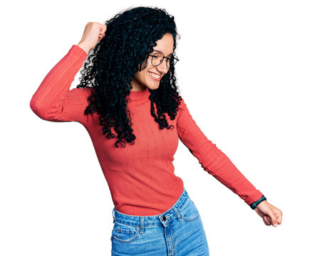 Young hispanic woman with curly hair wearing glasses dancing happy and cheerful, smiling moving casual and confident listening to music