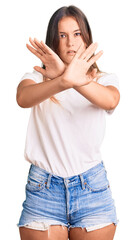 Beautiful caucasian woman wearing casual white tshirt rejection expression crossing arms doing negative sign, angry face