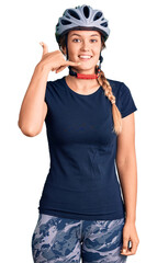 Beautiful caucasian woman wearing bike helmet smiling doing phone gesture with hand and fingers like talking on the telephone. communicating concepts.