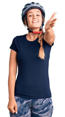 Beautiful caucasian woman wearing bike helmet smiling friendly offering handshake as greeting and welcoming. successful business.