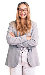 Young beautiful blonde woman wearing call center agent headset happy face smiling with crossed arms...