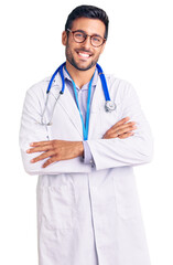 Young hispanic man wearing doctor uniform and stethoscope happy face smiling with crossed arms...