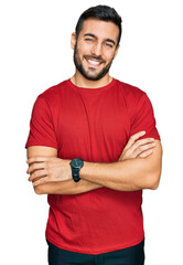 Young hispanic man wearing casual clothes happy face smiling with crossed arms looking at the...