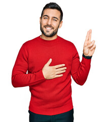 Young hispanic man wearing casual clothes smiling swearing with hand on chest and fingers up, making a loyalty promise oath