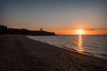 Fototapeta premium Waves on the sea during sunset. Relaxation, enjoyment. Journey to the ocean, peace and happiness. Colorful, bright, orange sunset. The sun shines through the clouds on the ocean. Beautiful wallpapers