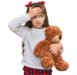 Little caucasian girl kid hugging teddy bear stuffed animal stressed and frustrated with hand on head, surprised and angry face
