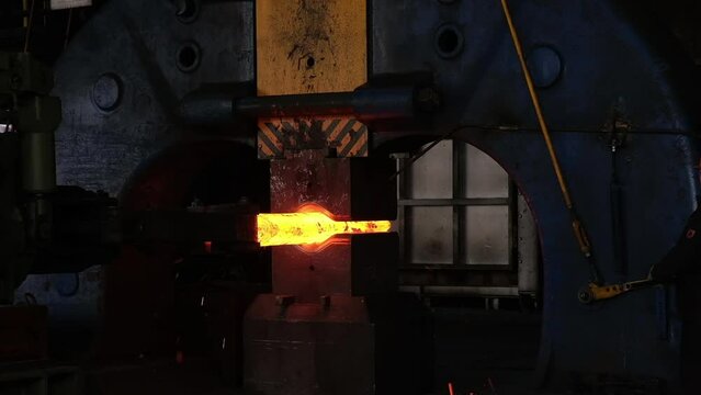 Pressing machine, smart machines, computer technology. Press operation, sparks, heat treatment. Blacksmith factory. Forging a large hot metal billet with an industrial forging press. Technical