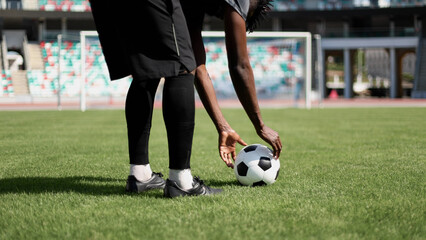 Obraz premium African American man playing football on the stadium field. A man runs with a soccer ball across the field.