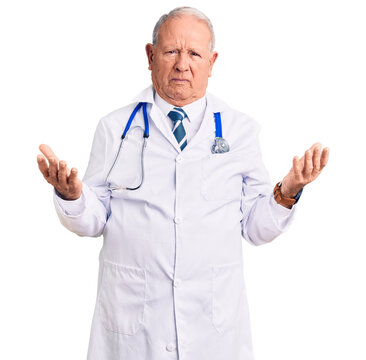 Senior handsome grey-haired man wearing doctor coat and stethoscope clueless and confused with open arms, no idea concept.