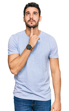 Young hispanic man wearing casual clothes thinking concentrated about doubt with finger on chin and looking up wondering