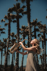 Woman with sax in nature among palm trees