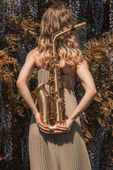 Girl with saxophones in nature , jazz music 
