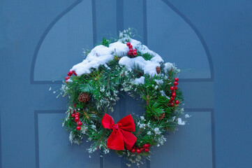 Beautiful Christmas wreath of fir branches with cones, rowan berries and a red bow