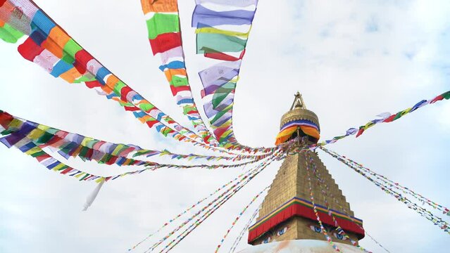 4K footage of multicolor Buddhist flags with mantras flapping under the gusts of wind on the background of blue sky on the Boudha Stupa (Boudhanath) in Kathmandu, Nepal.