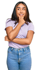 Fototapeta premium Young latin woman wearing casual clothes with hand on chin thinking about question, pensive expression. smiling with thoughtful face. doubt concept.