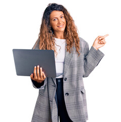 Young hispanic woman with tattoo holding laptop smiling happy pointing with hand and finger to the side