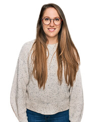 Young blonde woman wearing casual sweater and glasses with a happy and cool smile on face. lucky...