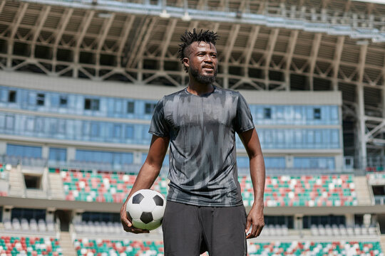 confident black football player holding the ball in his hand at the stadium