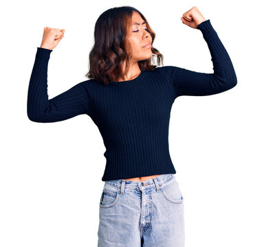 Young beautiful mixed race woman wearing casual clothes showing arms muscles smiling proud. fitness concept.