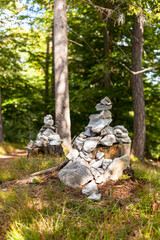 Steinturm zur Wegmarkierung auf Baumstumpf. 
Stone tower for trail marking on tree stump.