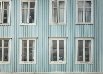 Fototapeta na wymiar Blaue Holzfassade mit weißen Fenstern. Tradtionelle Holzfassade in Schweden. Hellblaue Fassade. Blue wooden facade with white windows. Traditional wooden facade in Sweden. Light blue facade.
