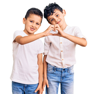 Couple of little brothers together wearing casual clothes smiling in love showing heart symbol and shape with hands. romantic concept.