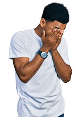 Young african american man wearing casual white t shirt with sad expression covering face with hands while crying. depression concept.