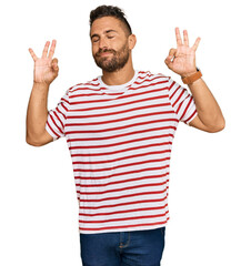 Handsome man with beard wearing striped tshirt relax and smiling with eyes closed doing meditation gesture with fingers. yoga concept.