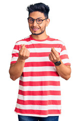 Handsome latin american young man wearing casual clothes and glasses doing money gesture with hands, asking for salary payment, millionaire business