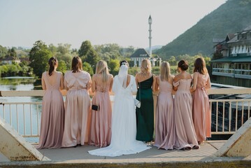 Bride and her bridesmaids standing on a bridge - obrazy, fototapety, plakaty
