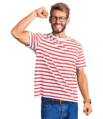 Handsome blond man with beard wearing casual clothes and glasses angry and mad raising fist...