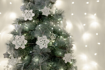 The Christmas tree is decorated with knitted snowflakes and lights