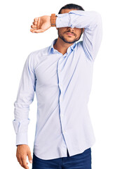 Young handsome man wearing business clothes covering eyes with arm, looking serious and sad. sightless, hiding and rejection concept