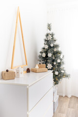 Fototapeta na wymiar The chest of drawers is decorated with a wooden Christmas tree, gifts and candles. Eco style