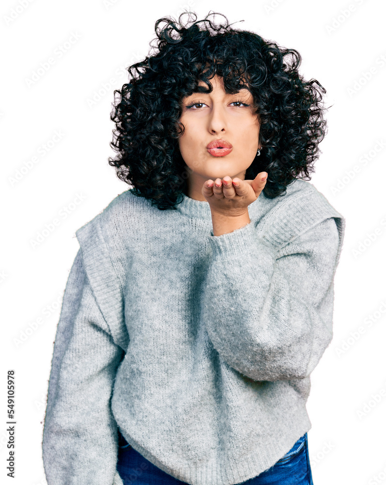 Poster young middle east girl wearing casual clothes looking at the camera blowing a kiss with hand on air 