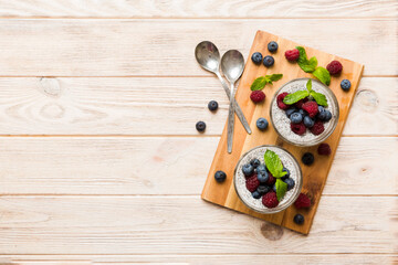 Fototapeta na wymiar Healthy breakfast or morning with chia seeds vanilla pudding raspberry and blueberry berries on table background, vegetarian food, diet and health concept. Chia pudding with raspberry and blueberry