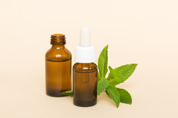 Natural Mint Essential Oil in a Glass Bottle. organic cosmetics with herbal extracts of mint on colored background