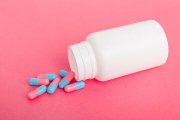 different drugs and health supplement pills poured from a medicine bottle health care and medical top view on colored background