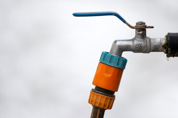 Garden faucet tap with frozen water drop in winter on snowy white blurred background