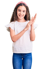 Cute hispanic child girl wearing casual white tshirt clapping and applauding happy and joyful,...