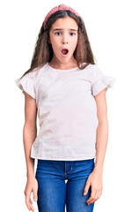 Obraz premium Cute hispanic child girl wearing casual white tshirt in shock face, looking skeptical and sarcastic, surprised with open mouth