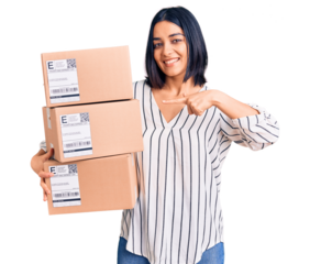 Young beautiful latin woman holding delivery package smiling happy pointing with hand and finger
