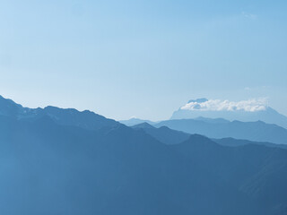 Light blue mountains in the distance, aerial perspective, mountain atmosphere. Beautiful mountain landscape, clouds over the peaks of the mountains,